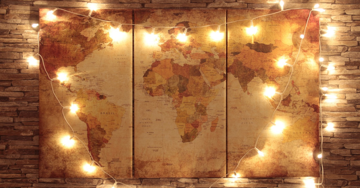 A string of fairy lights surrounds an old map of the earth that was divided into three sections and mounted to poster board before hanging on a wall