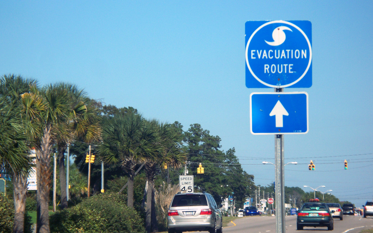 Evacuation Route Sign Along a Major City Road with Cars and Blue Sky