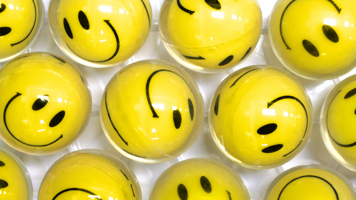 Glossy yellow balls with a smiley face lined up in rows depicting ignorance is bliss